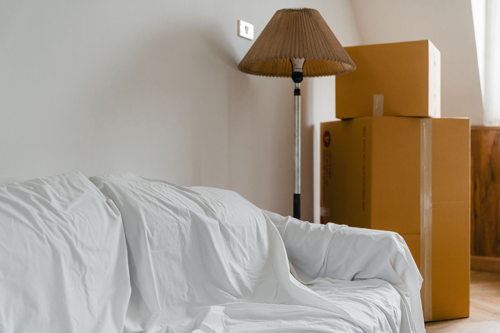 Abgedeckte Möbel und gepackte Umzugskartons in einer Wohnung vor der Haushaltsauflösung